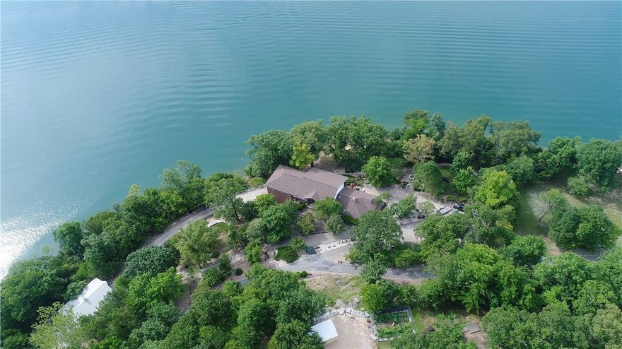 Sitting on 4.82 ac with 850’ of shoreline and lake views from EVERY room, this property is lake living at its best! Sitting on a point, there are no docks in front of the house to block the view. A private dock is around the corner & an additional slip in a community dock, both with lifts. This custom home features a great room with 21’ high wall of windows, quarter sawn oak floors, dining room, cozy den with woodstove & stone floors, bar with wine cellar, large master suite with a private deck, master bath with a claw foot bathtub/steam shower/sauna, master cedar closet with adjoining laundry room, kitchen with Viking appliances, library, safe room, large man cave with a workbench, craft/hobby room, covered patio with an outdoor kitchen with built in grills, hot tub to soak in the lake views, and a two car garage. There is a 30x40 Morton Building with two sets of garage doors for the ability to drive through. The entire property is beautifully landscaped in a gated community with paved roads. Rare find!