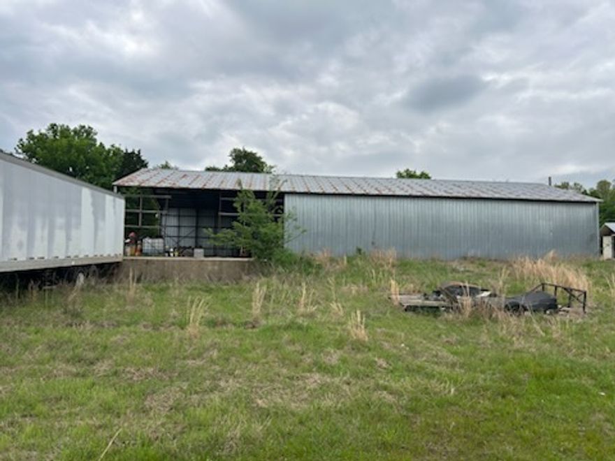 Metal building, office, 3 old mobile homes plus 20 acres.  It was used as a warehouse. Metal siding and metal roof; Also there are two docks.  Building is 40 x 80 on concrete slab.  There is one water meter and two electric meters.  Property is outside city limits.