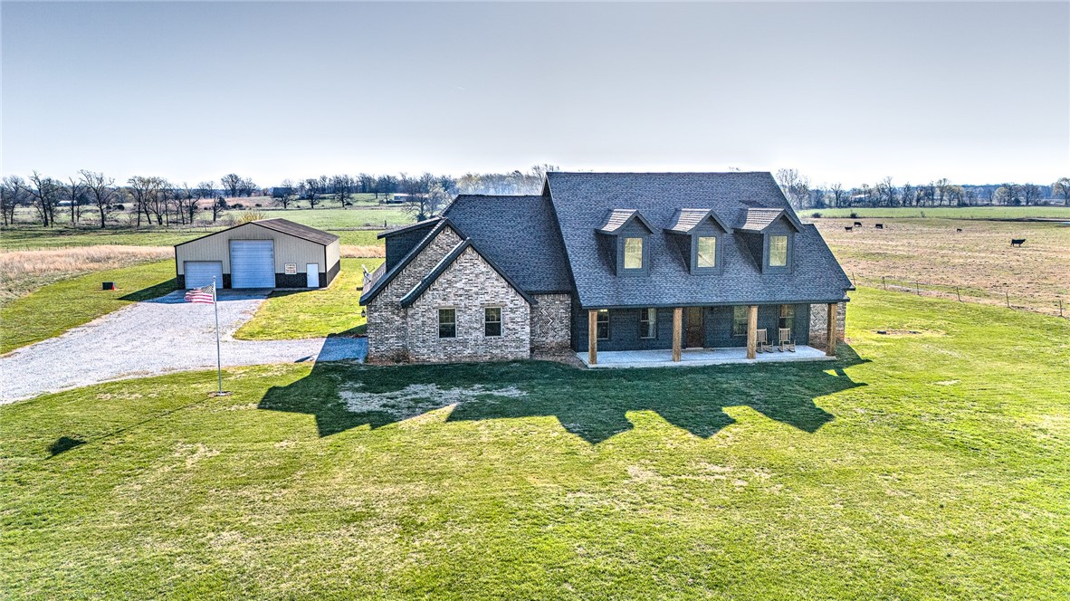 Immaculately crafted by its sole owner, this stunning residence boasts four bedrooms and four bathrooms. Noteworthy features comprise a striking ceiling treatment utilizing reclaimed barnwood, a gourmet kitchen equipped with a six-burner cooktop and double ovens, and exquisite granite countertops. A large walk-in pantry in the kitchen adds to the convenience. This property also features two oversized bedrooms upstairs, each with its own en-suite bathroom. Two inviting fireplaces on the main level offer warmth and charm. Nestled on a sprawling five-acre plot, along with a spacious steel trusted 60x40 metal workshop with RV sized pull-through garage doors on either side.