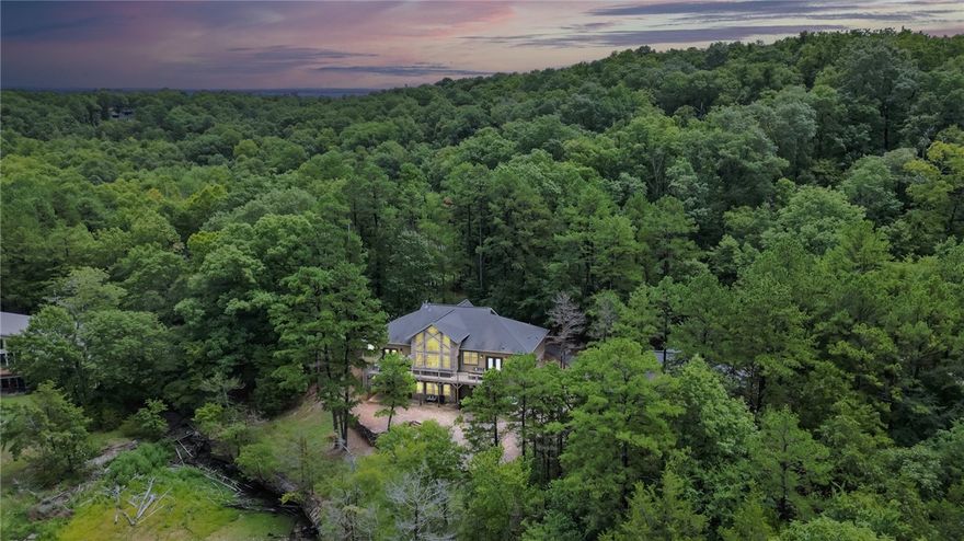 A slip in the community dock conveys with this lakefront property! Escape to a tranquil retreat where nature's beauty and modern comforts come together in perfect harmony. Welcome to this fully furnished, custom-built lake house. Thinking of sharing a lake house with your best friends? This home accommodates two families with ease! You'll find a suite including two bedrooms and a bathroom on each side of the shared entertaining space, complete with a rock climbing wall and amazing view! Downstairs you'll find a second living area, bar, and a bunk room. The 3-bay, oversized garage includes an extra tall bay to store a surf boat. Step outside to find a haven for outdoor adventurers. The slip in the community dock is a gateway to endless aquatic adventures. The fire pit is the ideal spot for stargazing, storytelling, or simply roasting marshmallows. Embrace the camaraderie of a community where like-minded individuals share in the joys of lakeside living! Please Note: Parcel Map is Incorrect according to surveyor.