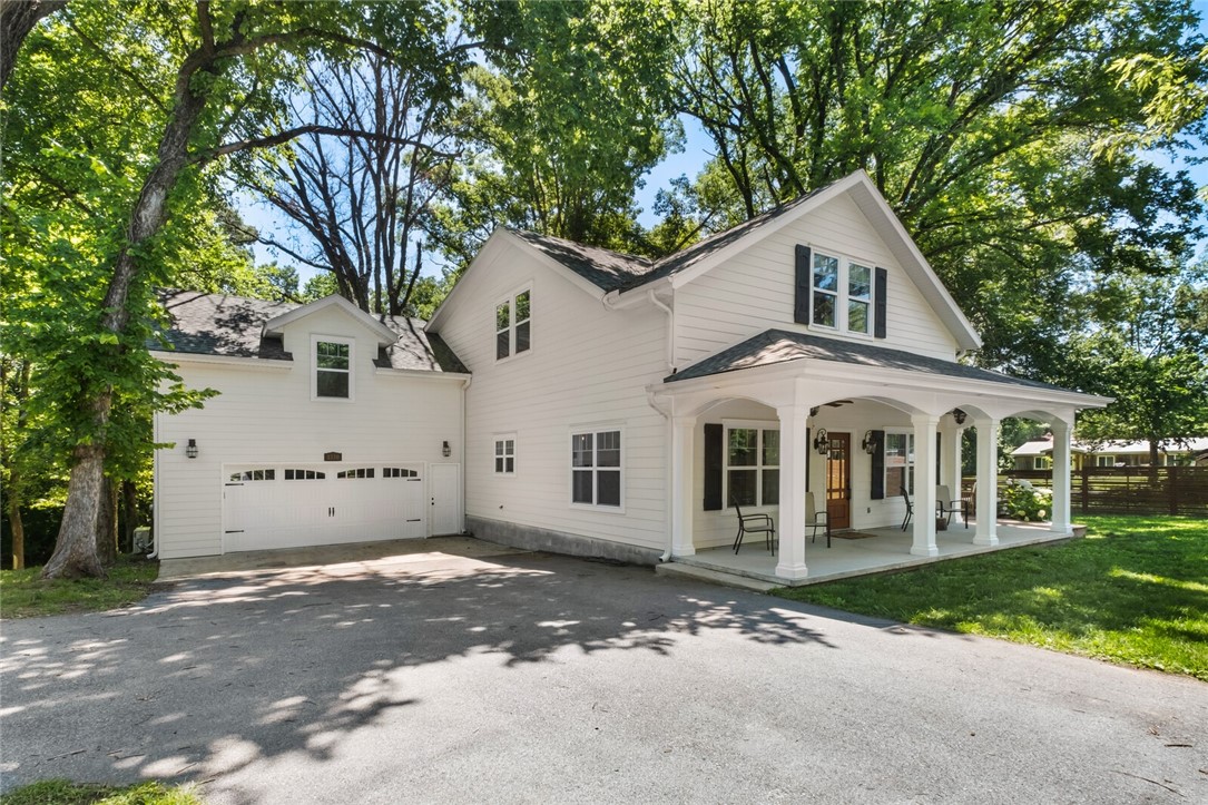 Charming modern farmhouse! This 4–5 bedroom, 3.5 bath home offers nearly 3,000 sq ft of well-designed functional living space. Open floor plan with vaulted ceilings, natural light, and designer touches throughout. Kitchen features large island and flows seamlessly into living/dining areas. Two primary suites—one on each level—offer flexibility for multigenerational living. Upstairs primary with hidden storage; downstairs suite opens to private deck. Bonus/media room provides a second living space or entertainment area. Inviting front porch, large back deck, mature trees, and raised garden beds create a serene outdoor setting. Historic outbuilding adds charm and versatility. Private backyard offers a peaceful retreat, while location provides quick access to Downtown Rogers and Walmart HQ. This thoughtfully designed home blends style, comfort, and convenience.