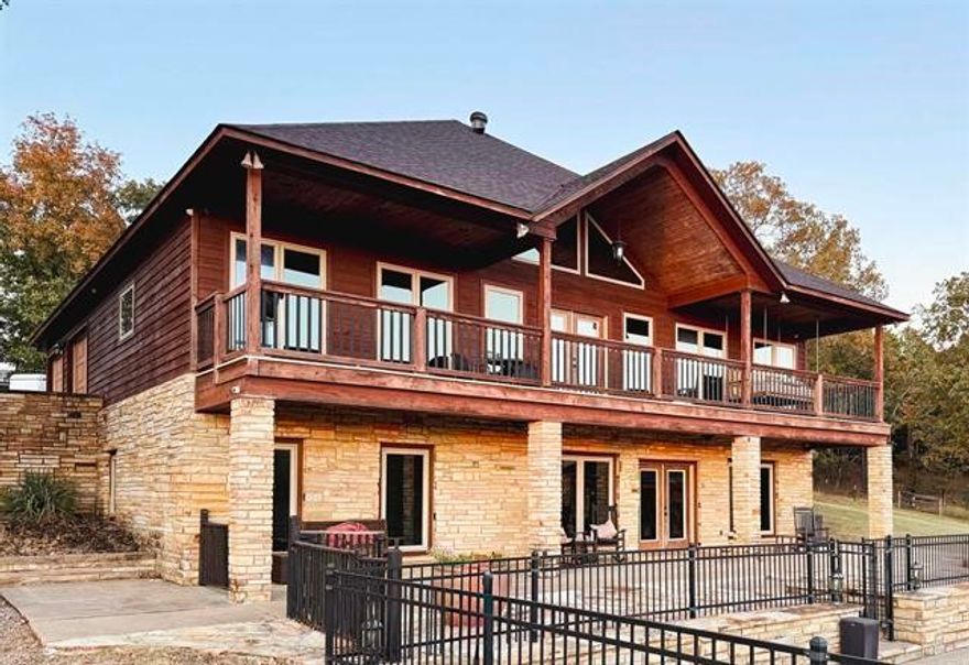 Nestled into the hillside on 40 m/l acres overlooking pasture and a stocked pond sits a beautiful lodge-style home. This custom two-story home features 6-inch concrete walls from ground to roof, plus a full kitchen and walk-in pantry on both floors. Upstairs, the main living room showcases a warm tongue-and-groove vaulted ceiling and a wall of windows that flood the space with natural light. Cozy and inviting, the back porch is ideal for sunset views. The primary suite includes a walk-in tiled shower and large closet, while the office offers built-in desks and ample storage. Downstairs is perfect for entertaining or large families with an expansive open area for a big-screen TV, pool table, and dining tables. Patio doors lead to a stunning in-ground pool with firepit and outdoor kitchen, plus a full bath. Two bedrooms and a full bath complete the lower level. The cross-fenced pasture includes a barn, a 24x36 shop with 12-ft lean-tos and loft, and a detached garage with bonus room.