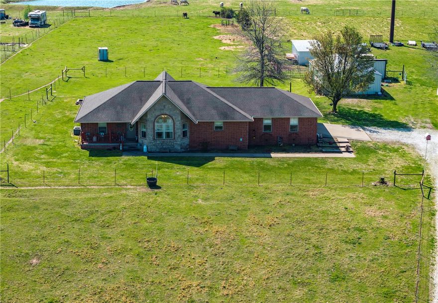 Looking for a hobby farm? With 5 acres of rolling pastures that are crossed fenced, a shop with cement floors and electric, livestock sheds and pens, plenty of room for a garden and a well-maintained home., this one could be it!  Key features include new flooring throughout, split floor plan, large bedrooms, formal dining space, vaulted and trey ceilings, granite counters, stainless appliances, pantry, all electric, side load garage and an extra room in garage that's perfect for an office, hobby or 4th bedroom. The primary suite offers a big closet, separate walk-in shower, whirlpool tub and double sinks. Guest bedrooms are large enough for queen beds with plenty of floor space. Living room is open to dining area with a free-standing pellet stove. Covered porch and deck for outdoor entertaining. Detached 24 x 36 insulated shop, loafing sheds and pens, great garden spot all located midway between Siloam Springs and Fayetteville on a paved road.