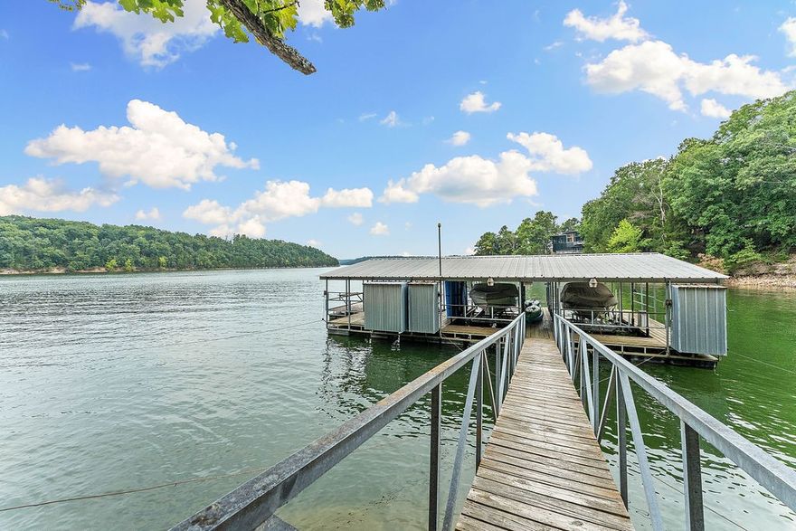 Lakefront living doesn't get better than this. Tucked along the water's edge, this fully furnished, turnkey property offers 180-degree panoramic views, a private self-adjusting boat slip, and everything you need to enjoy lake life from day one. The main home features 4 bedrooms, 3 baths, vaulted ceilings, wide-plank flooring, and a chef's kitchen with gas range, griddle, and heat lamp. The lower level adds bunk space and a second living area — perfect for large groups. A separate guest house with its own kitchen and bath creates incredible flexibility, whether you're hosting family or generating short-term rental income. This is the rare combination of private dock access, luxury finishes, and multi-unit capacity that's nearly impossible to replicate. Use it as your personal retreat, an income-producing investment, or both. Either way, it delivers.