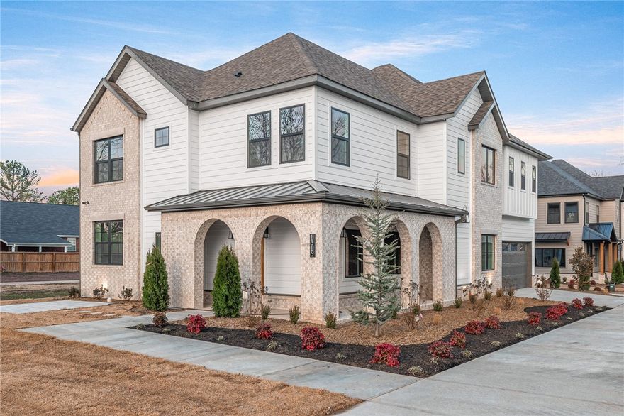 Nestled on a private drive in north downtown Bentonville, The Enclave at Bella Vista Road offers four custom homes blending sophistication with modern comfort. This 5-bed, 3.5-bath residence features a soothing color palette, brushed gold accents, designer lighting, and matte white oak floors. The living room centers around a cozy fireplace with custom glass cabinetry. The main-level primary suite includes a feature wall and a spa-inspired bath with onyx lighting, marble tile, dual showerheads (including rain), and seamless glass. Upstairs, find a large family room, two bedrooms with a Jack & Jill bath, a secondary suite, and a flexible fifth bedroom or office. The outdoor space includes a front porch, patio, grilling terrace, and a fully fenced, landscaped yard. Just minutes from Bentonville, this home offers timeless luxury.