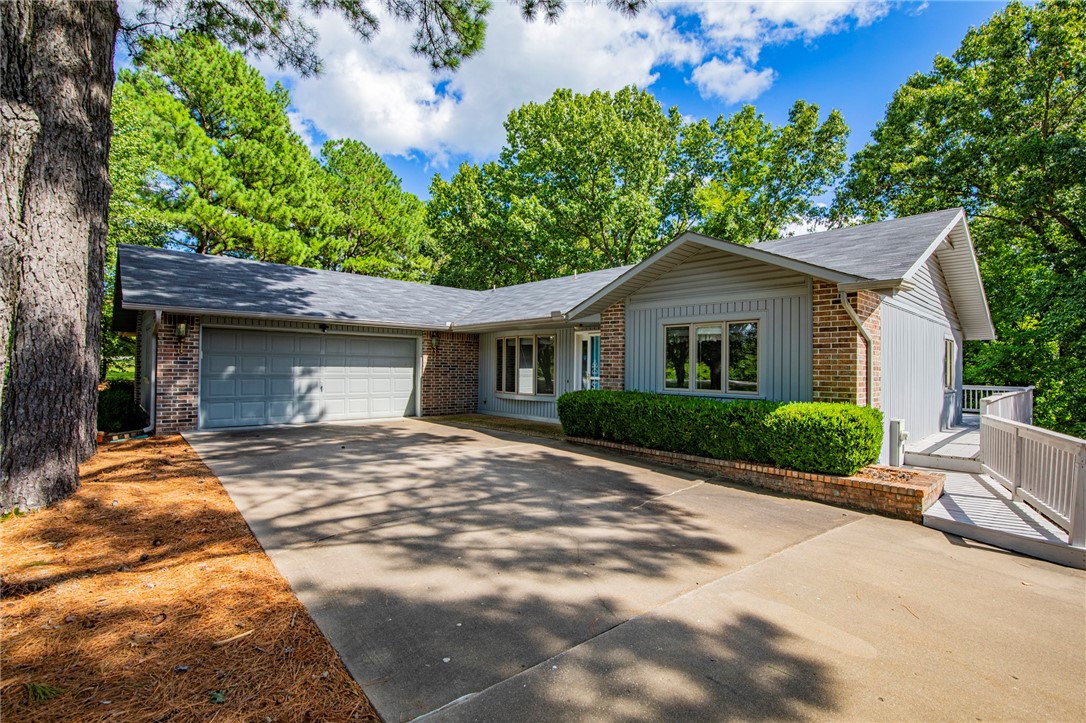 Come see this charming Bella Vista home near Loch Lomond and Lakepoint Restaurant/Marina. One-level, split floor plan with a cozy living room featuring a lovely fireplace. Some of the standout features of this home is the expansive wrap-around deck, an oversized garage with storage shelves, and a secluded sunroom. Abundant natural light throughout. New roof installed in July 2021. A perfect retreat for those who love the outdoors and a warm, inviting atmosphere