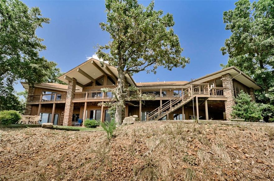 Beaver Lake View home w/community boat slip! This custom built lakefront estate, has plenty of windows and outside space to enjoy the view all year long. The home features an open floor plan with gourmet kitchen, formal dining, gorgeous stone fireplace and beautiful vaulted ceilings. Large master suite , spa-like bath, and attached office with Murphy bed. Spacious artist studio or office with large windows. The lower level is home to a second living area with stone fireplace, kitchenette, 2 guest suites, a workshop, and indoor potting room. Enjoy the outdoors with a screened porch, large deck, lower tiled patio that has space to add an outdoor kitchen, stone patio, and 6.71 acres!