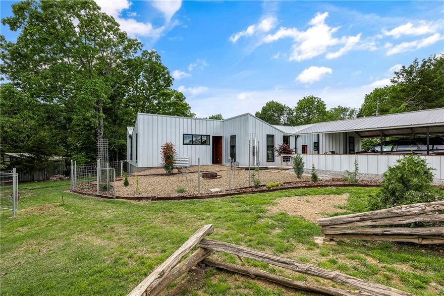 This one-of-a-kind home is tucked away in a peaceful, park-like setting near the lake—offering privacy, flexibility, and sustainable living. With its bright, open layout and large windows, the home feels connected to nature while still offering all the comforts of life. Relax or work from home on the private deck. Designed with eco-friendly living in mind, it has solar panels, a rainwater catchment system, and durable, low-maintenance metal siding. Perfect for those who love flexibility and an organic, eco-conscious lifestyle. The property includes a rental cabin and yurt, both with two full bathrooms nearby—great for family visits, guest stays, or extra income through short-term rentals. Multiple matching outbuildings, chicken coops, a storage shed, and an animal shelter make it easy to start a small homestead, hobby farm, or simply enjoy wide-open space. Minutes from the lake, I-49, and Rogers, this special property offers a unique mix of peace, practicality, and opportunity—ready for your next chapter.