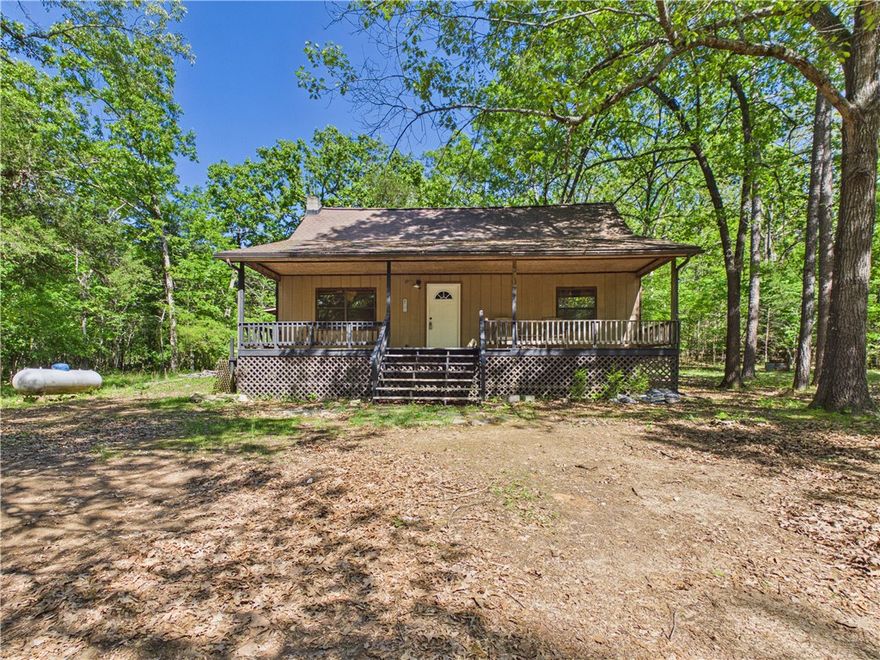 Tucked just beyond the city limits of Flippin, this charming 2-bedroom, 2-bath cabin offers a rare opportunity to create your ideal retreat. Set on 2.5 wooded acres, the property is rich with natural beauty, featuring mature trees and established flowerbeds that bring color and character to the landscape. Inside, the living room welcomes you with striking wood beams and a cozy gas log fireplace—an inviting focal point with plenty of rustic charm. While the home is ready for updates, it provides the perfect canvas to design a personalized getaway, full-time residence, or investment property. Outdoor enthusiasts will love the location—just 1.5 miles from the White River and only 5 miles from Bull Shoals Lake—making fishing, boating, and recreation easily accessible.  Selling As Is.