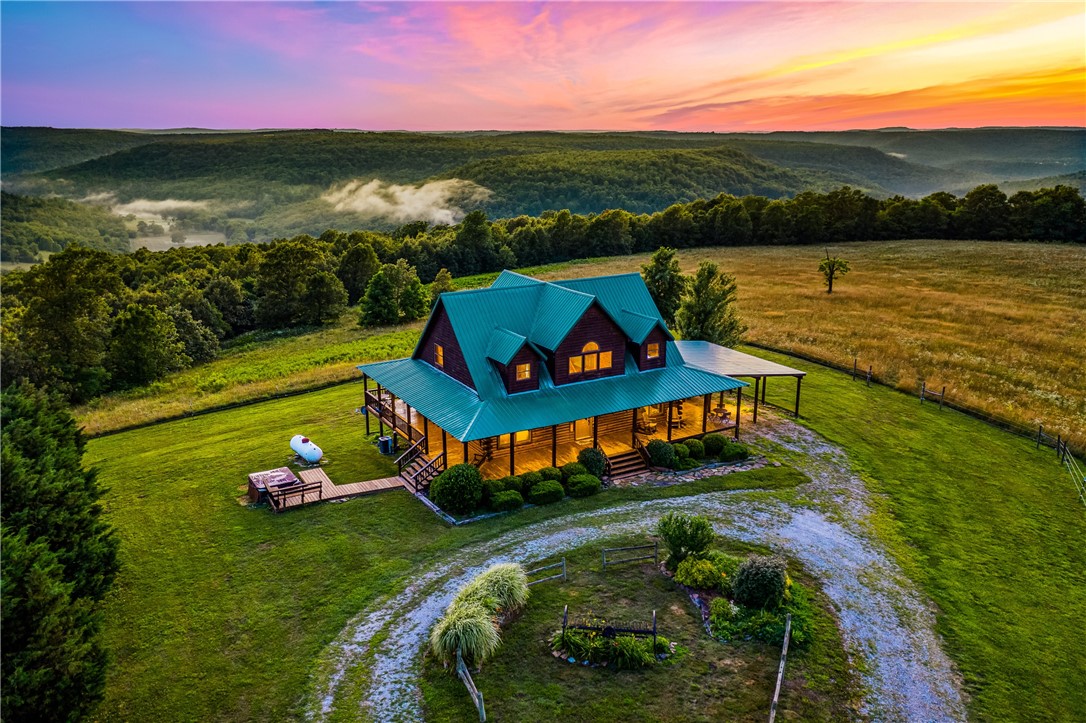 Here's your chance to own this rare Newton County property with 94+/- acres having a nice mix of pasture, hardwoods, a spring and spectacular mountain sunset views from your custom-built Log Cabin, AND one of the renowned "Mountain Springs" natural springs supplies fresh water to the home. This unique property offers 3 bedrooms, an office, 2.5 baths, an open floor plan highlighted by vaulted ceilings and a stunning catwalk that separates the upstairs bedrooms. Enjoy year-round outdoor living on the wraparound covered porch, where you can take in spectacular long-distance mountain sunset views or relax in the hot tub under the stars. Equestrian enthusiasts will appreciate the horse barn and pasture with fabulous trails to ride nearby. Bring your convertible and ride the scenic mountain highways because the drive is asphalt, leading from a state highway. There's a 24 X 30 carport attached to the home. Selling furnished and with appliances and hot tub conveying!