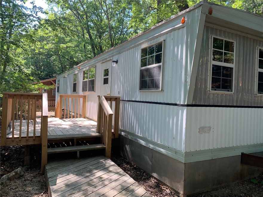 Single wide trailer with 552 sq ft; the remodel has been started but has not been completed; paint has been purchased, and carpet in outbuilding could carpet both bedrooms; also wood stove that can be easily reconnected; premium parking to accommodate several vehicles. Beautiful wooden walkway down to trailer with lots of stacked stone walls along the way. Outbuilding 8' x 16'. Refrigerator, stove, and dishwasher all convey with property; come and take a look!