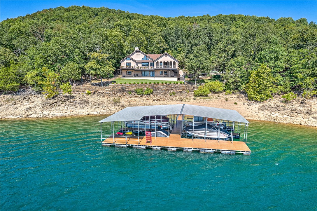 Exquisite retreat with amazing views nestled on 1.84 acres right along the shores of Beaver Lake. This home boasts a Private 4-slip dock, with 3 slips featuring boat lifts and 1 slip equipped with 2 PWC lifts. The expansive 8'x66' swim deck provides the ultimate waterfront experience. Notable upgrades include a 25KW Kohler whole-house generator, a new roof installed in 2019, and two new HVAC systems in 2018. A water softener was added in 2021, and the deck surface replaced in 2023. Enjoy breathtaking lake views through new Anderson windows (2019) on the upper floor. This lakeside oasis is a testament to luxury living, featuring the primary bedroom on the main floor, and updated kitchen with Thermador Appliances. Downstairs you are met with a large family room and entertaining area, two bedrooms and office that could also be used as a bedroom. Above the garage features a bunk room with ensuite. Don't forget the extra oversized detached garage for all of your hobby or storage needs. Your waterfront dream awaits!