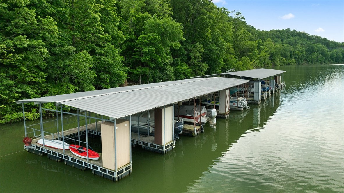 Charming Beaver Lake home nestled on 1.48 acres, featuring a co-owned boat dock with your own designated slip, providing direct lake access for boating, fishing, and endless water recreation! This beautiful home features a brick and stone exterior, vaulted ceilings, custom crown molding details, and gorgeous hardwood floors throughout the main level. Inside offers ample space with 3 bedrooms, 3 bathrooms, an office/flex room, and a spacious walkout basement for additional living. The warm and inviting kitchen features rich wood cabinetry and an oversized refrigerator that conveys. Step out onto the 3-tiered back porch to relax or entertain while taking in the peaceful, wooded views! The partially complete, ready-to-finish detached garage adds flexible potential to suit your needs - whether for storage, a workshop, or future guest space. Don't miss this rare opportunity to own the perfect combination of lake access, a private slip, usable acreage, and convenient proximity to both Springdale and Fayetteville!