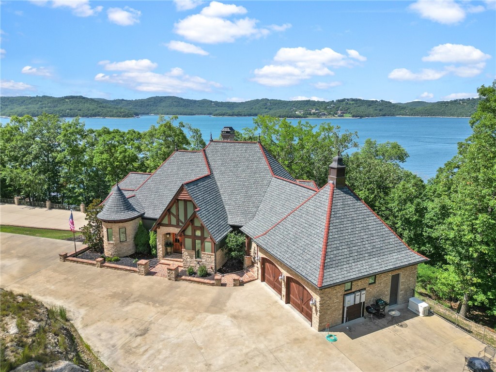 A breathtaking lake front home with a beautiful view. This home sports a fun Old World look on the front with a lot of glass on the back. It boasts of 2 kitchens, 2 living rooms, 3 bedrooms with a bonus room serving as a 4th bedroom, 5 bathrooms and loads of storage. From the lower porch follow a gentle path to a 2 slip (12x30) PRIVATE DOCK with swim deck waiting for all of the fun times on the water. A heated/cooled 1,824 sq. ft. storage shop with kitchen and 1/2 bath is a big bonus on the property. Endless possibilities for storage of water toys or maybe a super MAN CAVE. Let your imagination run! Nature lovers...there is an eagles nest on the acreage, and caves to explore on the bluff.
Too many details to list, ask your agent for the amenities and updates lists. Security system surveillance. Most furnishings to convey. This one is set up for memory making that new owners will enjoy for years to come. Can't wait to visit and hang out on one of the wrap around porches overlooking the lake.
