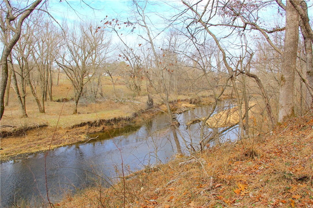 Welcome to your peaceful seclusion in the middle of town, with eight wooded acres and an excellent build site. As you approach this property along the private drive, it feels a little like stepping back in time to a simpler way a life. Enjoy the sights and sounds of the beautiful Osage Creek flowing through the property year round, or stroll down to its banks for some fishing and swimming. Reclaim some lumber from the old barn to incorporate into your dream home perched atop the central ridge with a sunset view over the creek, and sit back and enjoy the wildlife in your own backyard. Plus, this storybook homesite is within minutes of the Pinnacle Promenade, downtown Bentonville, and XNA airport! You don’t have to shop NW Arkansas real estate very long to realize what a rare find this is, especially when you combine the gorgeous creek, the wooded privacy, and the outstanding location.