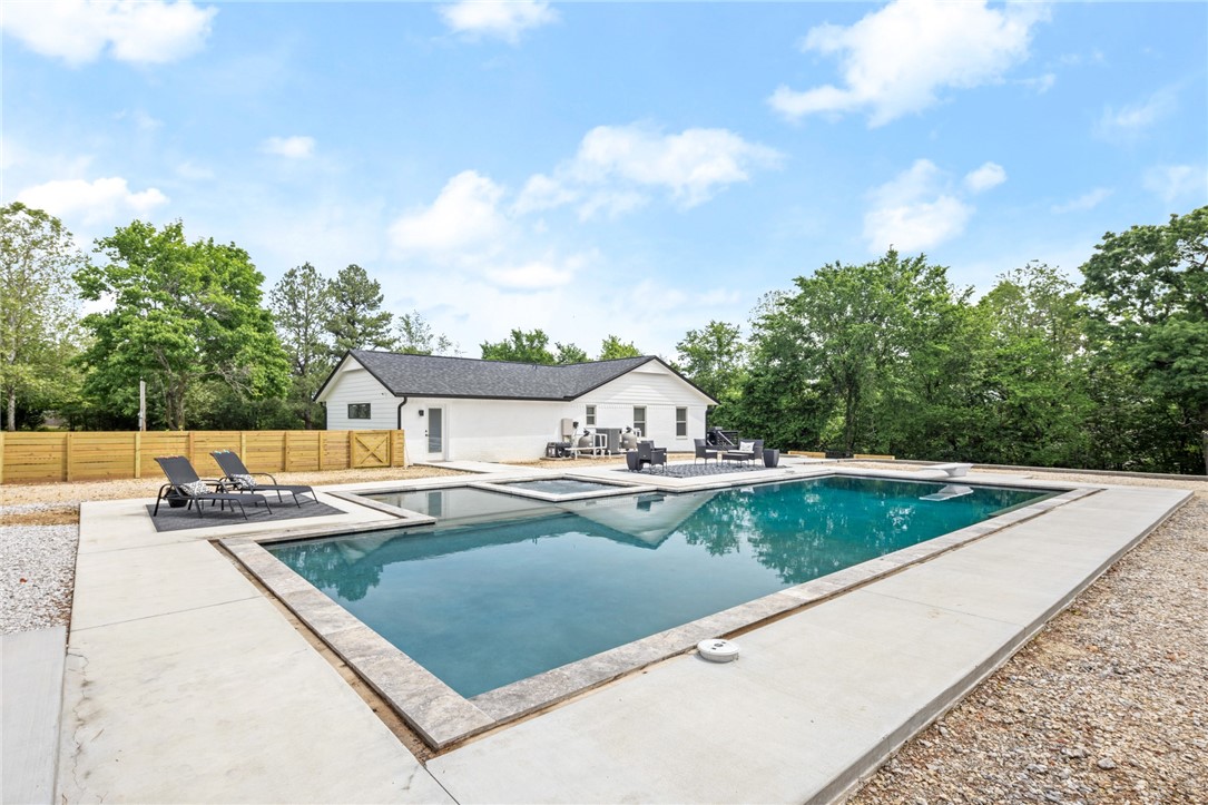 This property has it all! Nestled in a prime location on 2.5 acres, this stunning property boasts a fully upgraded 2,744 sqft main house featuring 4 bedrooms and 3 bathrooms, including two master suites and a 1500 sqft 2 bed 1.5 bath garage apartment for a total of 4200 heated and cooled sqft! Modern aesthetics define the interior with new porcelain tile flooring, fresh paint, a new roof, and a newly constructed heated salt water pool complete with a built-in 12 person hot tub, 17' shallow end for water spots, and a baja deck. Adding to the allure is the spacious garage apartment that includes a full kitchen and laundry, and a gameroom with a storm shelter. A vast 2,000 sqft, 3-bay heated and insulated metal shop building presents endless possibilities for contractors or business owners needing substantial space for equipment. This property is a versatile gem perfect for both residential comfort and commercial utility. The house and garage are on separate electric meters. See attached features and upgrades