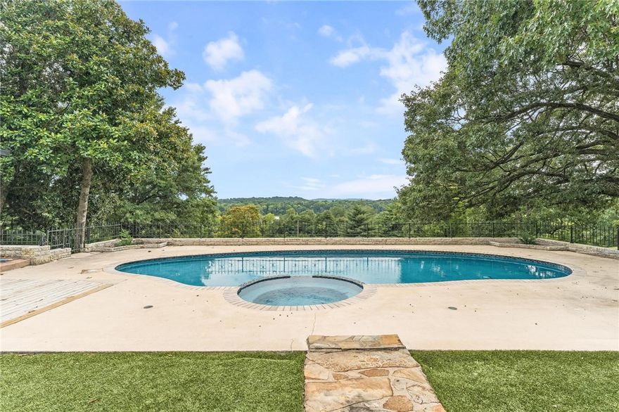 Iconic Mid-Century Estate with Lake Fayetteville Views–A Springdale Legacy. Step into a piece of Springdale history with this architecturally significant home, originally built in 1950 by renowned local builder and city icon Sandy Boone for Joe and Gretchen Steele. Perched on 4.41 acres with unparalleled view of Lake Fayetteville, this one-of-a-kind property offers nearly 7,000 sq ft of beautifully designed living space, including a 2,500 sq ft separate gym. Constructed with rare fossilized limestone block, the home's timeless mid-century design is enhanced by recent, high-end updates. The primary suite, completely remodeled in 2025, features dual spa-like bathrooms, refined finishes, and a serene, private retreat with modern elegance. Seven expansive sliding glass doors line the back of the home, seamlessly blending indoor and outdoor living while providing panoramic views of the newly resurfaced pool, cabana with outdoor kitchen, and the surrounding natural landscape—a true gem in Springdale’s real estate market.