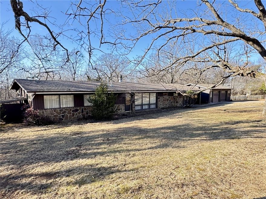 Nestled in the coveted Mt. Sequoyah area, this mid-century modern 3-bedroom, 2-bath home blends timeless architecture with serene natural surroundings. Walls of windows flood the home with natural light and connect the interior to the outdoors. Local stone, warm wood floors, vaulted beamed ceilings, and a striking stone fireplace with tongue-and-groove accent wall create a warm, architectural feel. The kitchen features a gas cooktop with beautiful sunset and nature views. Enjoy a fenced backyard and multiple balconies ideal for entertaining or relaxing in the private, tree-filled setting. Additional features include a large workshop with potential for extra living space, a separate oversized two-car garage, small barn, and lean-to for storage. Situated on nearly a full acre bordering peaceful woodlands and wildlife, on a quiet low-traffic street.