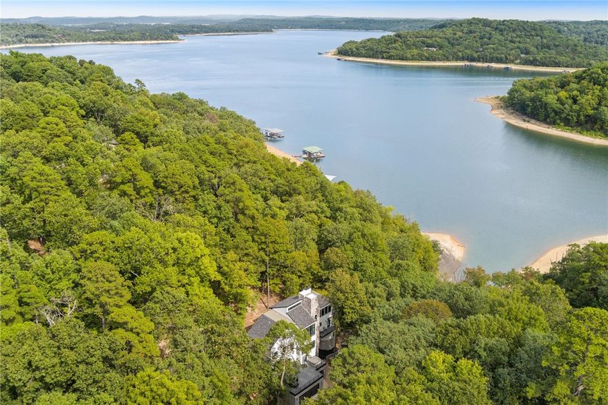Lakefront Living with Stunning Amenities! This exceptional property offers direct access to Beaver Lake, with a public beach and boat launch just steps from your front door—giving you all the convenience of lake access without the maintenance of a private dock, a true advantage for lake lovers. Enjoy breathtaking lake views through floor-to-ceiling windows. With three spacious living areas spread across multiple levels, the home is thoughtfully designed to provide both privacy and ideal spaces for gathering. A residential elevator adds both convenience and accessibility. Inside, all three bedrooms feature ensuite bathrooms, complemented by a dedicated office space for remote work.  The seller has also added additional parking, perfect for boats, trailers, or extra vehicles. For outdoor enthusiasts, the Monument Bike Trails at Hobbs State Park are just 6 miles away.  Located just 10 minutes from highly desirable downtown Rogers, this lakefront retreat perfectly blends luxury, flexibility, and adventure.