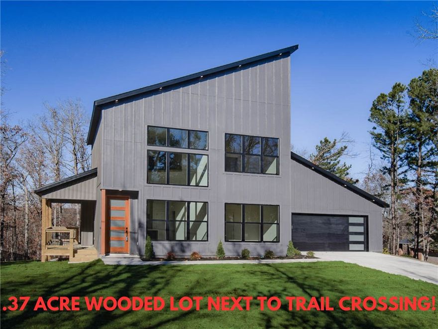 This modern new construction home sits on a large .37 acre wooded lot next to the Taylor Homestead Trail Crossing! Bentonville schools! This stunning home showcases modern custom finishes throughout! 2BD's + office. Step inside to discover beautiful floor-to-ceiling custom cabinets and a huge waterfall island, perfect for entertaining family and friends. The kitchen is also equipped with stainless steel appliances, including a gas range. No carpet! Breathtaking two-story living room with huge windows going up to the ceiling! Retreat to the primary suite with a stunning walk-in tile shower that elevates your everyday routine. Guest bedroom is located on the main level. As a bonus, the buyer can receive $3,500 in closing costs when using the builder's preferred lender.