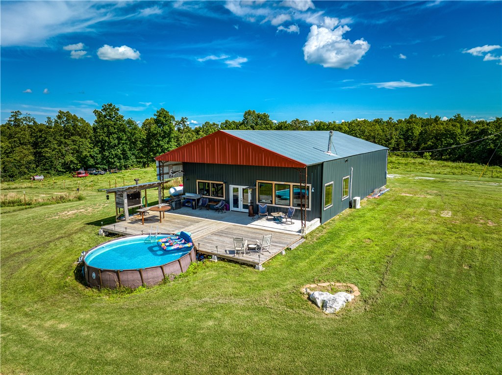 Hay Barn HALLELUJAH! Step into barndominium living at its finest! Situated on 13.76 acres, this 1 BR 2 BA converted hay barn is so unique and has so much to offer. There is a good mix of woods and pasture with 2 ponds, and workshop space to boot. There are established garden beds, an amazing outdoor kitchen and the sunsets from the deck are GORGEOUS! All the logs, doors and stairs in the home are recycled from a 100+ year old cabin. There is barnwood that was recycled from an old barn. The tub in the downstairs bath is a customized stock tank. The gorgeous tile 6 x 6 shower upstairs is complete with a large rain head shower. Behind the wood stove is a custom steel heat plate with a gorgeous custom mantel from the same cabin as the other amenities. The custom island is steel and concrete and includes the gas cook top. There is a built-in electric oven. Walk out onto the deck that leads to your new pool and open your mind to all the meals you can enjoy from the custom smoker that you prep on the unique island.
