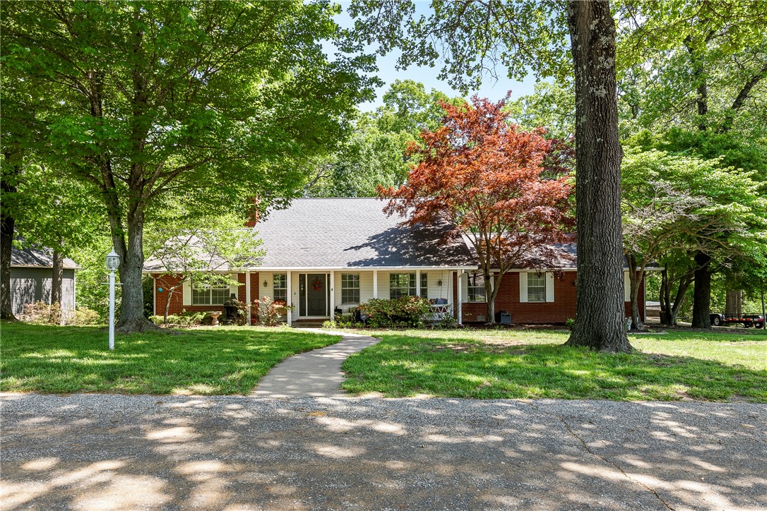 Curb appeal! This traditional style home is perfectly located on a lovely street, tucked in a beautiful 1.63 acre setting between Downtown Rogers and Beaver Lake. Primary bedroom and bath on the main level, with 2 bedrooms & bath plus a bonus room upstairs. Many updates including new kitchen & island with Negresco granite, new flooring, and new upstairs carpet. Enjoy privacy & the views to the woods out the many back windows or from the deck. Don't miss the unique bonus spaces - the heated/cooled media/bar room off the garage, an upstairs nursery or office, and an under-the-stairs lighted storage nook. The large front porch w/swing, laundry room w/lots of cabinet storage, oversized garage w/extra paved parking, as well as the additional tankless water heater, Nest thermostat & Ring doorbell round out a long list of amenities. Come tour today!