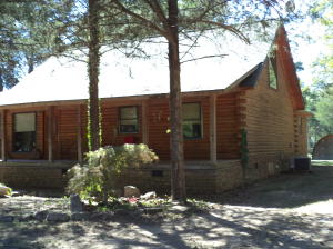 LOG HOME NESTLED on wooded lot in quiet subdivision. Covered front porch to enjoy the breezes, open floor plan has 15' cathedral ceiling, loft and 3 br 2 bath. Ch&A one year old, roof 6 yrs, newer appliances. 2 outbldgs in large back yard.