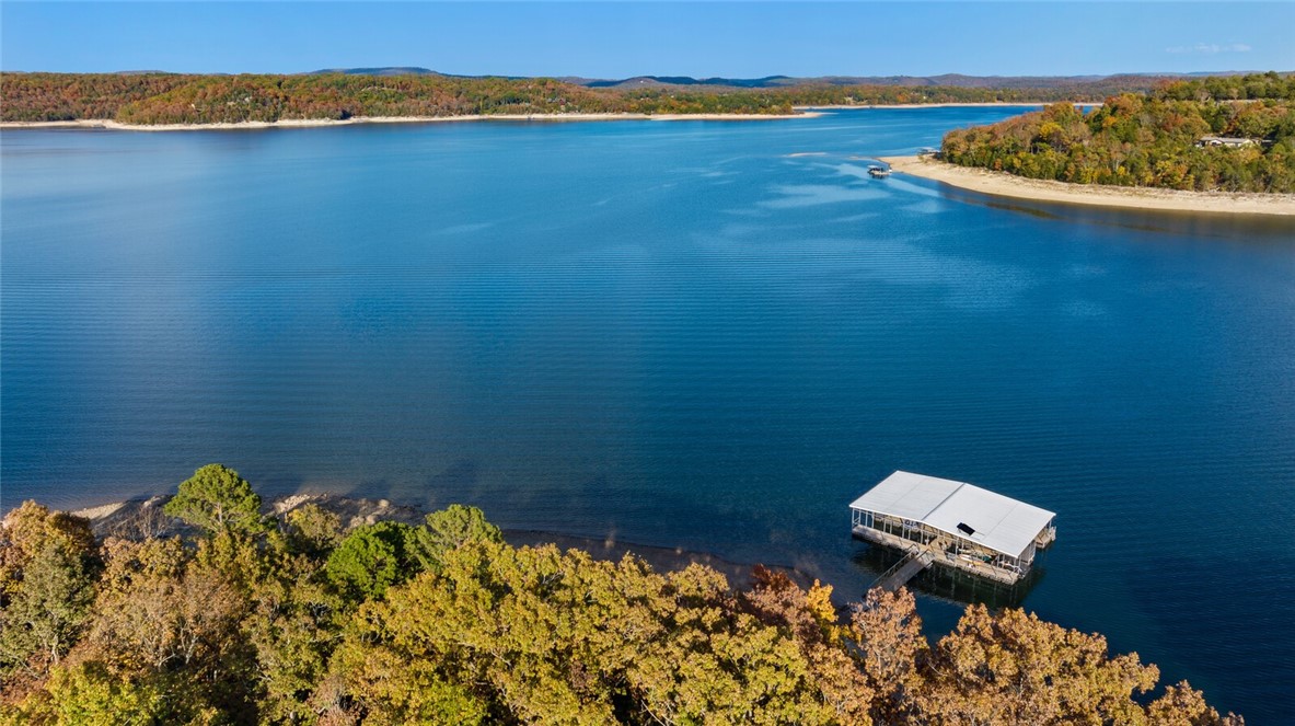 Nestled on 5.79 acres, this enviable lakeside retreat includes a cozy home, a premier 2nd buildable lot, approximately 1,700 ft of Beaver Lake frontage & effortless water access! With 4 bdrms & 3.5 baths spread across 2,968 sf of living space, this home provides ample room for family & guests to relax & unwind. Special features include picture windows framing year-round panoramic lake views, floor-to-ceiling stone wood-burning fireplace, spacious kitchen & open dining area, expansive outdoor deck and seamless lakefront living with water activities just steps from your door. The property boasts a hard to find co-owned boat dock with 2 boat slips & large swim deck, perfect for your watercrafts & ensuring you're always ready for a day of aquatic adventure or simply soaking in the lake views. Located on a prime lake location & off the shores of Shaddox Cove, this lakeside gem is just a short 10-mile drive to downtown Rogers, offering the perfect balance of serene seclusion & urban convenience. Also for see ML #1295484