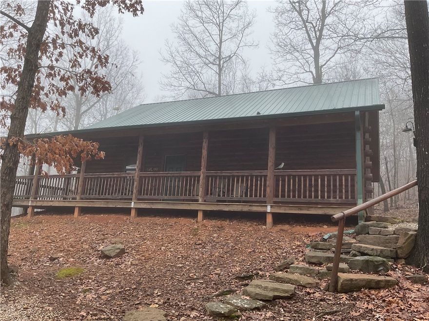 Serenity at its finest—just 4 miles from the breathtaking Buffalo National River near Ponca.  This 16.47 acre retreat offers privacy, natural beauty, and true Ozarks charm. This meticulously maintained log home features 3 bedrooms and 2 baths, blending rustic character with everyday comfort. A recently paved driveway adds convenience and curb appeal. Inside, enjoy a warm and inviting living area centered around a cozy gas log fireplace—perfect after a day on the river or exploring the outdoors. The well-designed layout provides comfortable living, and the home is fully furnished for a true turnkey opportunity. Relax on the expansive wrap-around porch overlooking peaceful views. The acreage includes a pond and natural spring supplying the home’s water, enhancing this secluded setting. Ideal as a full-time residence, vacation getaway, or income-producing investment property.