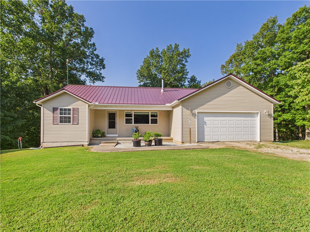 Peaceful Country Living Just Minutes from Harrison. Escape to privacy without giving up convenience! This 3-bedroom, 2-bath home sits on 3.34 wooded acres and offers 1,562 sq. ft. of comfortable living space plus a full unfinished basement—perfect for storage or finishing to add more room. The basement includes a drive-in garage door for easy access. Car lovers, hobbyists, and RV owners will love the 30' x 50' metal shop building with a 14' overhead door for RV storage and an additional garage door for workshop space. The main home also features a two-car garage on the main level. Enjoy the seasons year-round from the heated and cooled glassed-in sunroom, where you can watch deer and birds right outside your window. Tucked away in the trees, this property offers peace, wildlife, and privacy—yet is just minutes from all that Harrison has to offer.