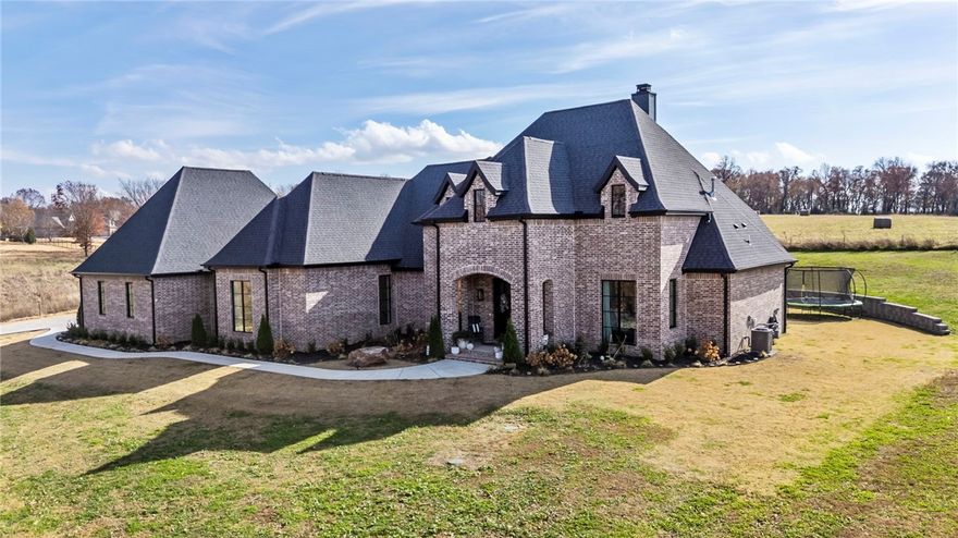 This home is a designers dream located in a prime location in Elm Springs. Custom built at every turn, this one is sure to wow you. Current owners are using this as a 4 bedroom, plus sitting room, private office, and a bonus/media room.  The majority of the living space is on the first level. Upstairs is a guest bedroom suite and media room. Every bedroom has an ensuite bathroom and every sq inch was curated and well thought out. No shortcuts were taken on this home. This home screams luxury, convenience, and private! Situated on 1.78 acres, enter the property onto your long wooded driveway that leads up to your estate. The amenities are outstanding and include a quartz waterfall island, white oak wrapped beams, black floor to ceiling windows, the most amazing tile work in every single bathroom,, 48” gas range, a dry bar, butler’s pantry, pot filler, woodburning fireplace, hardwood floors, 2 primary closets, large covered patio, and an oversized side load 3 car garage! This is the one you've been waiting for.