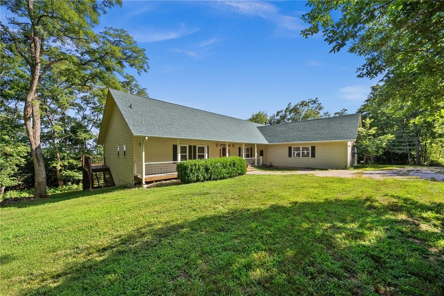 Perched on a hill above Beaver Lake amidst 23.61 acres of Oak and Pine trees, this secluded home reveals an amazing view of the lake. The split floor plan offers dual main suites, which makes this home perfect for families who want everyone under one roof. 2 bedrooms, full bath, and kitchenette afford guests or mother-in-law with a little more personal space than a traditional guest room would allow. You will find the Primary bedroom, bath, half bath within the 3115 sq. ft. on the main floor. The living room has picture windows spanning the entire wall giving you a sunfilled living, dining room, and kitchen. The living room also boasts a beautiful wood burning fireplace that you can cozy up to on chilly  days.  The nicely equipped kitchen and spacious laundry room with washer, dryer, and shower complete the main floor. Stairs down lead to 3115 sq. ft. of heated, cooled, and plumbed unfinished walkout basement ready for your desired use. The shop area of the basement has a wash basin and toilet for your convenience.
