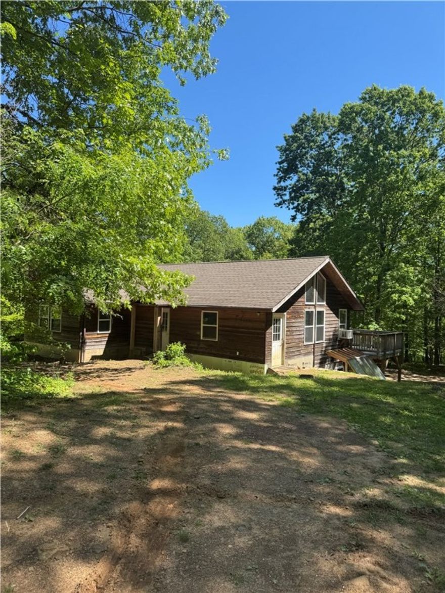 Who's ready to move back to the land or have the weekend getaway for hunting or fun? This 2800 sqft home (1400 finished) sits on a lovely 7 acre parcel (to be surveyed from parent 55 acre tract) with stately hardwood timber, trails, and garden plot. Built in 2006 the 3 bedroom 2 bath upstairs and 1400 feet of workshop space with a 1/2 bath in the walkout basement. Home is all electric and has a low production well and rain catchment system. The oak flooring was milled from the property. The cherry cabinets and electric range make a welcoming kitchen. Enjoy your coffee or happy hour from the first level deck. The seller has built an extensive trail system to ride his mountain bike. Lots of wet weather streams and wildlife make this a true rural delight. Huntsville bus route and 30 minutes to the Mulberry River. No central HVAC. Wood stove is the basement and window units keep the home climatized but a mini split system could easily be installed. Live fully off grid by adding solar.