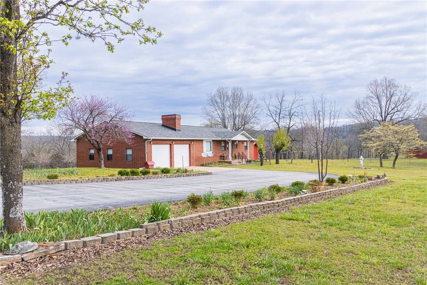 Tucked away along a quiet county road, this 3-bed, 2-bath brick home sits on 34.24 acres m/l and offers a setting well-suited for those looking to live a little more independently. The land is a mix of 10 acres m/l of pasture and the balance in timber, with terrain that lies level to gently rolling. A natural spring and creek run through the property, providing a reliable water source and adding to the land's usability. Perimeter fencing is in place, along with a fenced area surrounding the home. Owned by the same family, the property features established fruit trees, a garden, and new deck to enjoy the setting. Outbuildings include a 30'x20' two-stall barn with tack room and 12'x16' shop with concrete floor and electricity. The home includes a two-car attached garage and a comfortable, functional layout. Located less than 15 minutes from town, this property offers privacy, usable land, and the kind of quiet that's hard to come by, while still keeping everyday conveniences within reach.