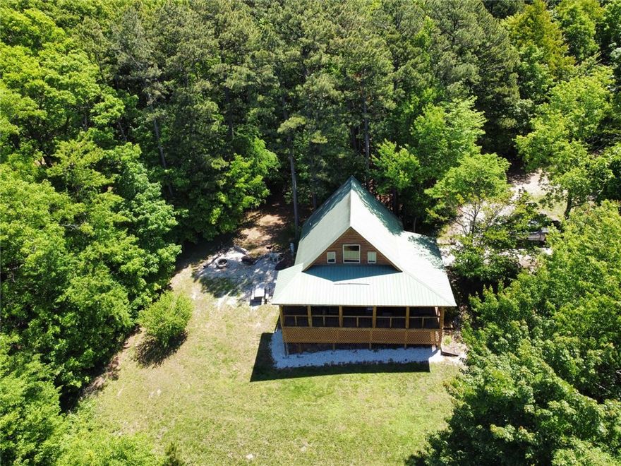 Tucked away in the heart of the Ozarks in Jasper, Arkansas, this charming cedar log cabin offers the perfect blend of privacy, scenery, and outdoor adventure. Surrounded by beautiful hardwood trees and breathtaking Ozark Mountain views, the property sits in a quiet setting just minutes from hiking trails, abundant wildlife, and the renowned Buffalo National River.
The inviting wraparound porch creates the ideal space for outdoor grilling, entertaining, or simply enjoying your morning coffee while taking in the peaceful mountain scenery. Inside, the cabin features a warm and welcoming open living area with rustic charm throughout, along with a spacious loft that offers additional sleeping space, a game room, or flexible living area.
Currently operating as a successful nightly rental since 2004, this cabin comes fully furnished with all contents conveying, making it a turnkey opportunity for investors or buyers ready to enjoy their own Ozark escape from day one.