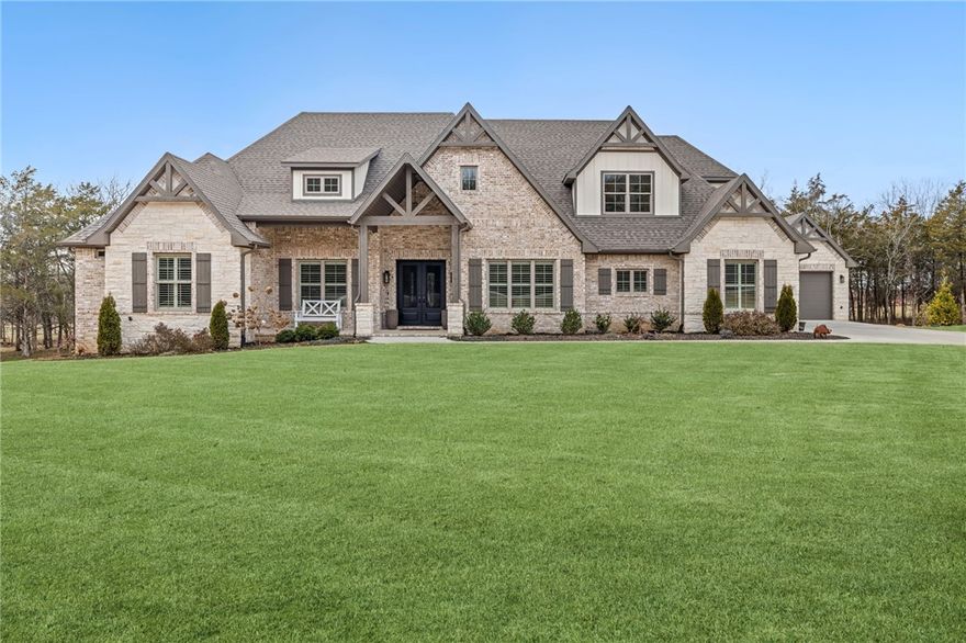 This stunning luxury estate sits on three pristine acres, just minutes from downtown Fayetteville and the University of Arkansas. Built for comfort and sophistication, it showcases exquisite craftsmanship and high-end finishes.
Step inside to soaring ceilings, abundant natural light, and thermally treated European oak flooring. The open-concept living area features a grand fireplace and custom built-ins, seamlessly flowing into a gourmet kitchen with KitchenAid appliances, a gas cooktop, a double oven, quartz counters, and ample storage. A formal dining room and breakfast nook provide perfect gathering spaces. 
The primary suite on the main level offers a private fireplace, spa-like bath, and spacious walk-in closet. Three additional bedrooms and an office are located downstairs. Upstairs, there is a media room, bonus room, and guest suite. The expansive covered patio was designed for year-round enjoyment, featuring an outdoor kitchen and fireplace overlooking a peaceful creek. Make this dream home yours today!