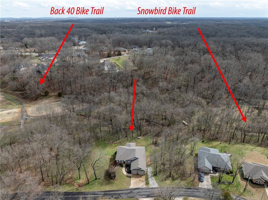 Located in one of Bella Vista’s most sought after outdoor corridors, this home offers direct access to the Snowbird section of the Back 40 Trail system just behind the property. Enjoy quick access to the golf course, Razorback Greenway, and nearby community amenities including a pool, playground, pickleball courts, golf, and a clubhouse, creating a true hub for active living.
The flexible floor plan features three bedrooms on the main level, an eat in kitchen, and a formal dining space that can easily serve as a home office. The walk out basement expands the living space with a large bonus room ideal for a gym, workshop, playroom, or media room, along with a fourth bedroom and ensuite bath.
Covered decks overlook a large, flat backyard surrounded by mature trees, offering wooded privacy, great curb appeal, and a peaceful bike friendly setting with direct trail access just steps away. SELLER IS OFFERING A $10,000 UPDATE ALLOWANCE.