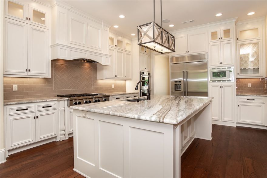 Sprawling entertaining spaces flow outside past the covered porch area to the stunning pool and tranquil wooded view beyond.  5 Bedrooms (3 downstairs, 2 upstairs), media/game room with wet bar, 4 full baths, powder bath w/access to covered porch area with fireplace, all set up for entertaining. Private wooded lot views continue from the inside out through generous windows maximizing the natural light. A Dream kitchen boasts marble counters, custom cabinets, a massive island w/sink, and KitchenAid appliance package. Stunning Master Suite, massive walk-in closet, soaker tub and walk-in shower. Beamed ceilings, Wood floors, & Designer fixtures enhance the exceptional craftmanship of this lovely home.