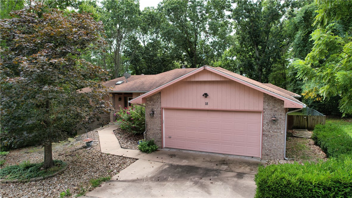 Welcome to 18 Walney Drive nestled in the peaceful surroundings of Bella Vista. Enjoy watching the birds from your large sunroom overlooking the backyard and forest behind the home. This home offers a comfortable layout with a spacious living area with fireplace, a sizeable kitchen, and a dining area perfect for everyday living and entertaining. You will find a large primary suite with walk in closet and view of the backyard. The second bedroom is also spacious for family or guests. The large flex room offers an area for a home office, workout room, den, or theater room. There is a nice workshop in the lower level with adequate space to store your bicycles or to work on your hobbies. This home offers easy access to golf courses, lakes, nature trails, convenient to Jane Walmart, and all the amenities Bella Vista offers including the bike trails. Whether you are looking for your full time residence, an investment property, or a quiet retreat you will want to schedule your showing to see this affordable home.