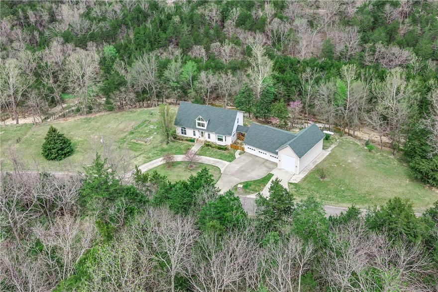 Tucked away on .82 acres along a creek in Holiday Island, this private 3-bed, 2.5-bath colonial offers 2,305 sq ft of stunning living space with soaring ceilings up to 29 feet. The dramatic great room flows into a 17x20 eat-in kitchen featuring granite counters, a bay window, and pantry. The primary suite includes a jetted tub and two walk-in closets. Upstairs bedrooms boast walk-in closets and a convenient Jack and Jill bath. Major updates include a 2023 roof with warranty, brand-new AC (2025), and triple-pane energy-efficient windows. The massive 41x17 RV garage with spray insulation and gas heat, plus a 25x36 three-car garage with attic storage, offer unmatched utility. A whole-home generator hookup, 3/4-acre fencing, and a covered outdoor living area make this home as functional as it is beautiful. Community amenities include a pool, golf, tennis, trails, and lake access. This one is truly special!