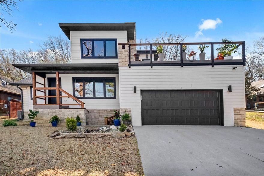 Gorgeous, breathtaking views greet you daily from the 500 SF rooftop deck, complete with a wood-burning fireplace and sweeping sunset views across Fayetteville—an exceptional space for entertaining or unwinding. Inside, the living area centers around a fireplace, with natural light pouring through a wall of windows. The reimagined kitchen, thoughtfully designed within the home’s original footprint, flows seamlessly and is ideal for any cook. A custom-built nook, perfect for pets or kids, showcases repurposed original flooring as a unique architectural accent. Main level features a private primary wing with western views, two walk-in closets, dual vanities, integrated laundry, and tiled walk-in shower. A second bedroom or office and an additional full bath complete the level. Upstairs, a light-filled landing with kitchenette connects two bedrooms and a full bath with original 1935 cast-iron tub and bonus space adds flexibility. The backyard preserves the stone foundation of the original homestead and a 2 car garage.