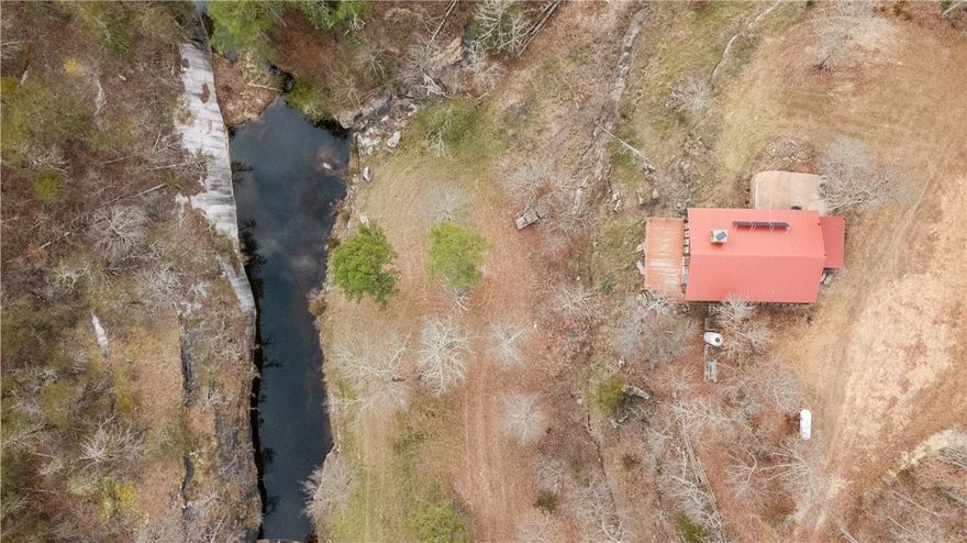 Tucked deep within the Madison County Wildlife Management Area, this extraordinary 80-acre inholding at Scotland Hollow offers a level of privacy, beauty, and seclusion rarely found in Northwest Arkansas. Completely surrounded by preserved public land, the property features a 1,200 SF rustic cabin with a proven off-grid solar system and new batteries, allowing true independence without sacrificing comfort. Less than 100 feet from the front deck is a year-round, spring-fed bluff pool with clear, swimmable water—an exceptional trophy feature that defines the property. Additional springs, caves, rock formations, and mature timber add to the sense of a private natural preserve. The bluff-lined pool sits at the base of towering stone walls and holds water year round, creating a natural swimming hole just steps from the cabin. The setting delivers unmatched tranquility, wildlife, and long-term protection, making this a rare opportunity to own a secluded Ozark sanctuary with remarkable character & end-of-the-road privacy.