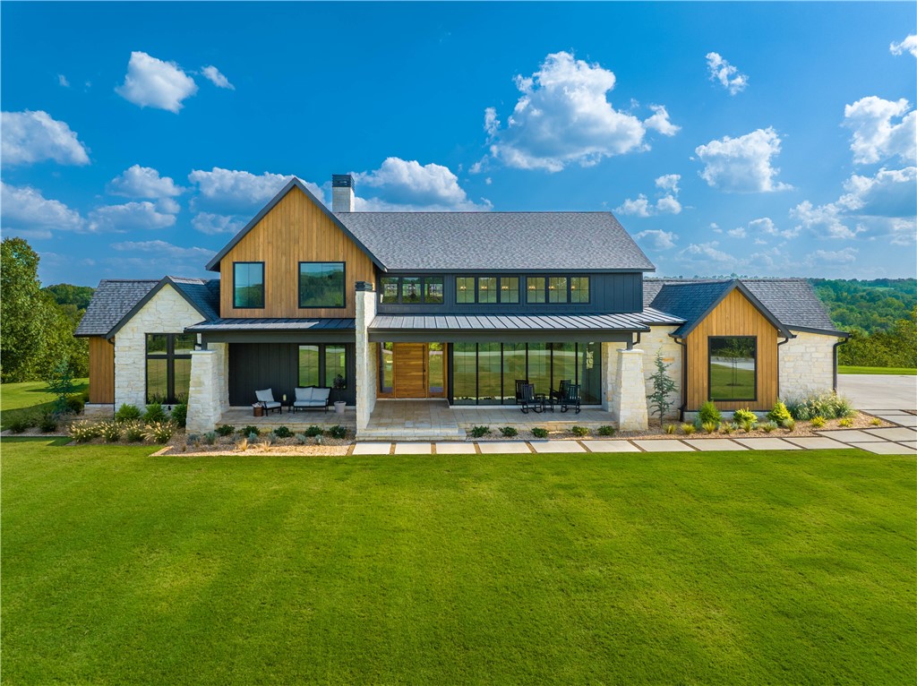 Discover a truly unique single-story custom home in the heart of Lowell, Northwest Arkansas. This modern farmhouse exudes timeless charm with 18-foot ceilings, open living spaces, and expansive floor-to-ceiling windows that seamlessly blend indoor and outdoor living. The kitchen is a chef's dream, featuring high-end finishes, a stunning waterfall island, and a pass-through door leading to a massive 38x20 covered outdoor living space overlooking picturesque Northwest Arkansas scenery. With 4 bedrooms and 4.5 baths, including a master suite with exquisite ceilings, this home offers both luxury and comfort. Accordion windows add to the allure of this exceptional property, making it the perfect retreat to enjoy the beauty of the region with family and friends.