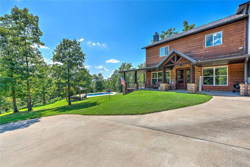 Discover your dream retreat on 15+ wooded acres by Beaver Lake just 10.5 miles from Downtown Rogers! This 4 bedroom plus office, 3 bath Lodge Style Home offers rustic charm with modern luxury. Enter through a secure, automatic gate and be welcomed by a beautiful private concrete circle drive. The open floor plan is perfect for entertaining, featuring custom barnwood cabinets, a gourmet kitchen with an oversized bar, granite countertops, gas stove, and a walk-in pantry. The primary suite boasts a private balcony with a partial winter view of the lake and a closet with a stack washer/dryer. Enjoy the outdoors with a metal roof, wrap-around porches, a 16x16 lower deck, a saltwater inground pool, and a charming gazebo. The property also includes a massive 40x60x16 fully insulated shop and a detached 4-car garage. Experience the feeling of living on vacation every day. Shown by appointment only. Contact us to schedule a private viewing and make this extraordinary property yours.