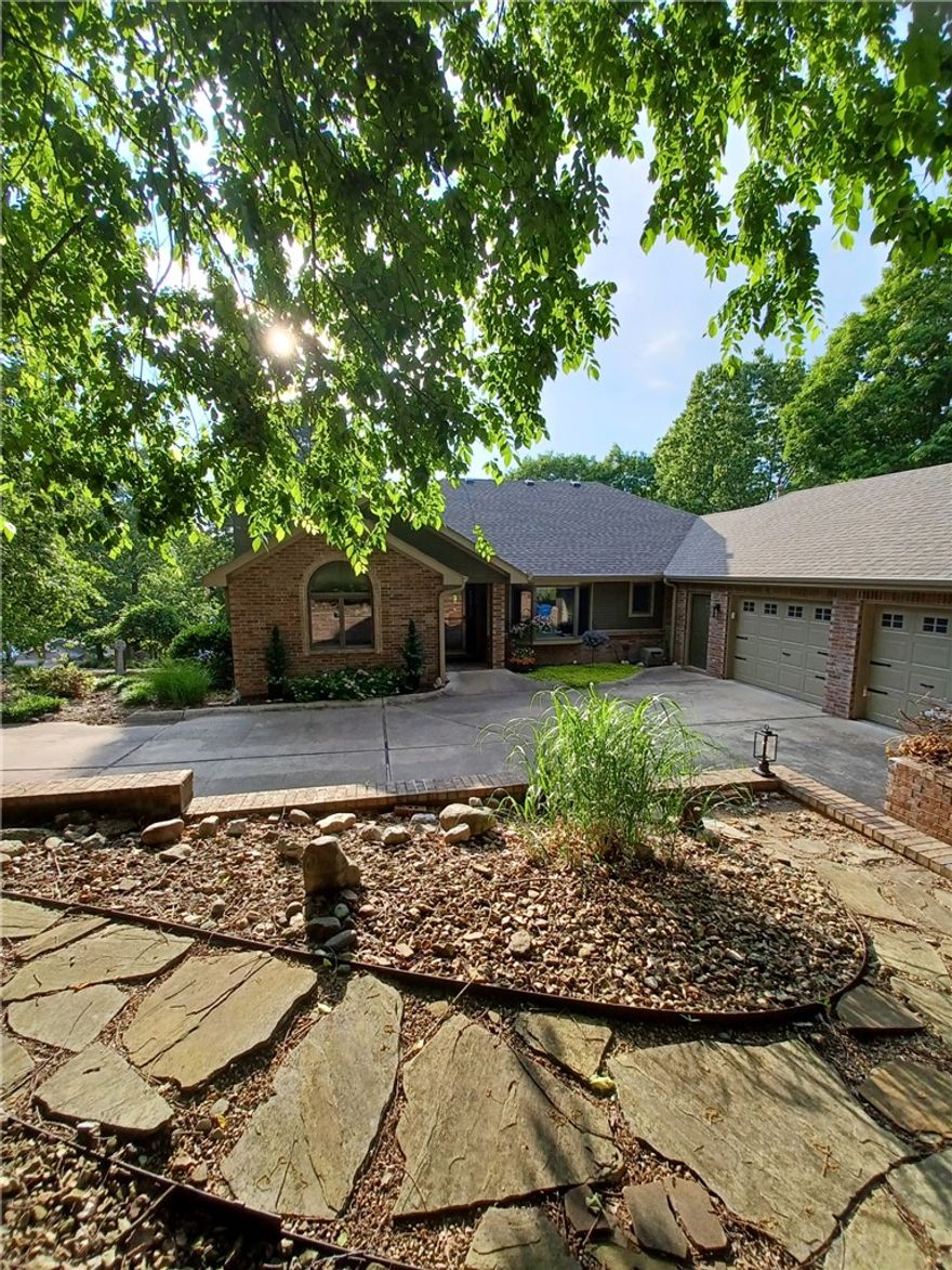 Experience Bella Vista living with this beautiful Gene Knight built custom home, sitting on a double lot. (.59 ac) Amazing views of Bella Vista's second largest lake, Lake Windsor. Perfect views from inside the home, on the covered deck up top and the patio below, across the back of the house. Relax on the deck taking in the view of an evening lake sunset. The entire yard is professionally landscaped with rock, flowers, shrubs and trees for the perfect mix of shade. Next to the oversized 2.5 car garage is a chain link fenced area for the pets. The spacious living room has a wood burning fireplace with access to the back deck . The large Primary bedroom has 2 spacious walk-in closets. The primary bath has separate sinks and a jet tub, as well as a step in therapy tub. 3 bedrooms, 3.5 baths, 2 living rooms, formal dining, eat-in-kitchen, sun room/office area, workshop and extra storage.  Enjoy a cup of coffee on the deck, or a bike ride right out your door to the trails, including the OZ Trails bike chair lift.