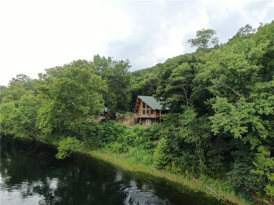 Situated on the banks of the White River below the Beaver Lake Dam, this 54-acre retreat offers privacy and solitude. Home to the Tailwater Club, it features a 2500 sq ft lodge and a 1500 sq ft clubhouse with stunning views, easy water access, and only the sounds of nature. The covered pavilion includes an outdoor kitchen, fireplace, and ample space for group gatherings. The 3bd/3ba Log Cabin Lodge boasts spacious rooms, a walkout basement, and a deck with downriver views. The clubhouse has 1bd/ba, personal lockers, a boot and rod room, and a fly-tying station. Its gathering room overlooks a newly completed tiered deck for socializing. Accessible by county road or the adjacent state park, it's 30 minutes from Downtown Rogers, 20 minutes from Eureka Springs, 10 minutes from Mtn Bike Trails, and 5 minutes from Beaver Lake. Private guided tours are available by appointment. Please also see the 42+/- Land MLS# 1296438