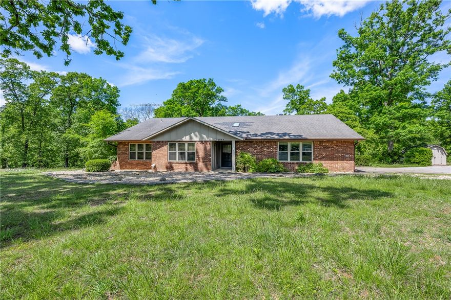 Tucked away in a prime Bentonville location, this all-brick home offers the perfect blend of privacy, space, and convenience—just minutes from world-class biking trails and the Razorback Greenway. Situated on 2.48 acres of serene, private land, this property provides a rare opportunity to enjoy both nature and proximity to everything Bentonville has to offer. A little cosmetic TLC and make it your own! Inside, the spacious living room serves as the heart of the home, featuring a stunning fireplace and a built-in wet bar—ideal for cozy nights in or hosting guests. Step outside to a large back deck designed for entertaining, overlooking your own peaceful acreage. This private retreat in an unbeatable location delivers comfort, character, and convenience all in one.