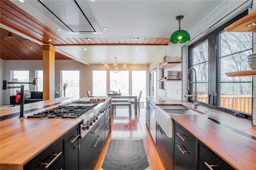 Exquisite lakefront home designed with a beautiful, upscale mid-century modern style. The details have been creatively thought out and expertly handcrafted in this jaw dropping remodel. Upon entering, your eyes are drawn to the wall of floor to ceiling windows flooding the house with natural light and endlessly breathless views of Lake Ann. The open concept chef's kitchen features a custom crafted, waterfall Sycamore countertop, Bosch appliances, and fully equipped walk in butler's pantry. The wood for the window sills and stair detail was sourced from trees on the property and handcrafted. Each bedroom, one on each level, has its own ensuite.  The upper level has a studio/art room and extra living space with french doors leading out to a private deck. The primary bedroom is its own retreat with a spa feel and walk out private deck.  The lower level has another living space which includes a custom designed theater sound system and wet bar. Custom stained glass throughout the house, commissioned from a local artist.