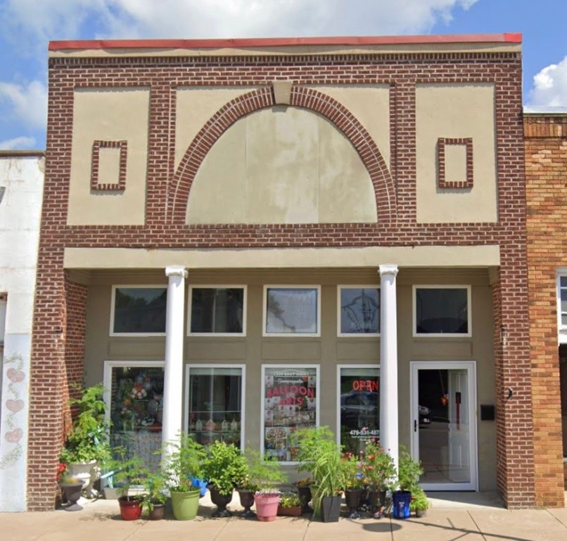 Great Opportunity on Gentry’s Main Street! Prime visibility and versatility define this 2,720 sq ft building on 0.08 acres, combining commercial workspace with upstairs living quarters. The street-front level features a welcoming lobby, private offices, storage space, and a half-bath, ideal for a small business or professional office. Located just off the rear is a warehouse area, complete with a full bathroom and washer/dryer hookup, plus both overhead and walk-through access.
Upstairs is a one-bedroom unit with its own entrance, offering a kitchen, living/dining combo, and full bath—perfect for an owner/operator, rental income, or private residence. Quality finishes throughout include tile and wood trim, concrete, simulated wood, laminate, and wood floors. Exterior is brick and stucco with a metal roof. Parking is convenient: two rear spaces, additional on-street, and a city lot just across the street.
