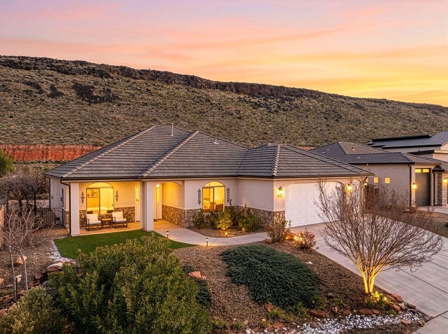 Located in Dixie Springs just 7 minutes from Sand Hollow Lake & the dunes, this 4-bedroom home offers elevated finishes, flexible living space, & beautiful mountain views while backing to a stunning natural hillside. The layout includes a versatile bonus/flex space ideal for a home office, gym, media room, or hobby area. The third-car bay has been enclosed to create additional usable space while maintaining a functional two-car garage. RV Parking. Open kitchen features quartz countertops, a large contrasting island, white cabinetry w/crown detail, updated pendant lighting, black hardware & fixtures, pantry storage & stainless appliances. The living room centers around a fireplace with built-ins and flows seamlessly into the dining area w/abundant natural light. The primary suite offers a spacious walk-in closet and an upgraded bath w/dual vanities, quartz counters, matte black fixtures, custom cabinetry storage, and a beautifully tiled walk-in shower w/bench seating. The backyard is a true highlight - professionally designed with artificial turf, mature palms, a tranquil rock water feature w/fountain, gazebo seating area & multiple entertaining spaces. Backing and siding natural hillside, the property provides exceptional privacy along w/expansive desert & mountain views that are difficult to find in this price range.
Located on Dixie Power and positioned near boating, golfing, off-roading, hiking & all the recreation Sand Hollow is known for, this home offers comfort, flexibility, and lifestyle in one of Southern Utah's most desirable neighborhoods.